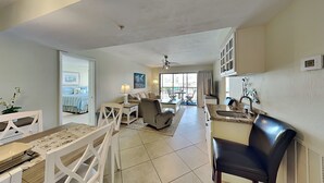A spacious living area with a dining table, chairs, a sofa, and a kitchen area with a sink and cabinets. - Santa Maria by Distinctive Beach Rentals (Fort Myers Beach)