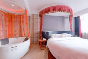 Una habitación de hotel moderna con una cama grande, una bañera curva y una mesita auxiliar.