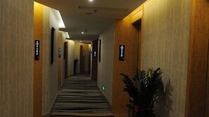 Passadís d'hotel amb parets de fusta, catifes amb dibuixos de ratlles negres i blanques i senyals il·luminats que indiquen els números de les habitacions.