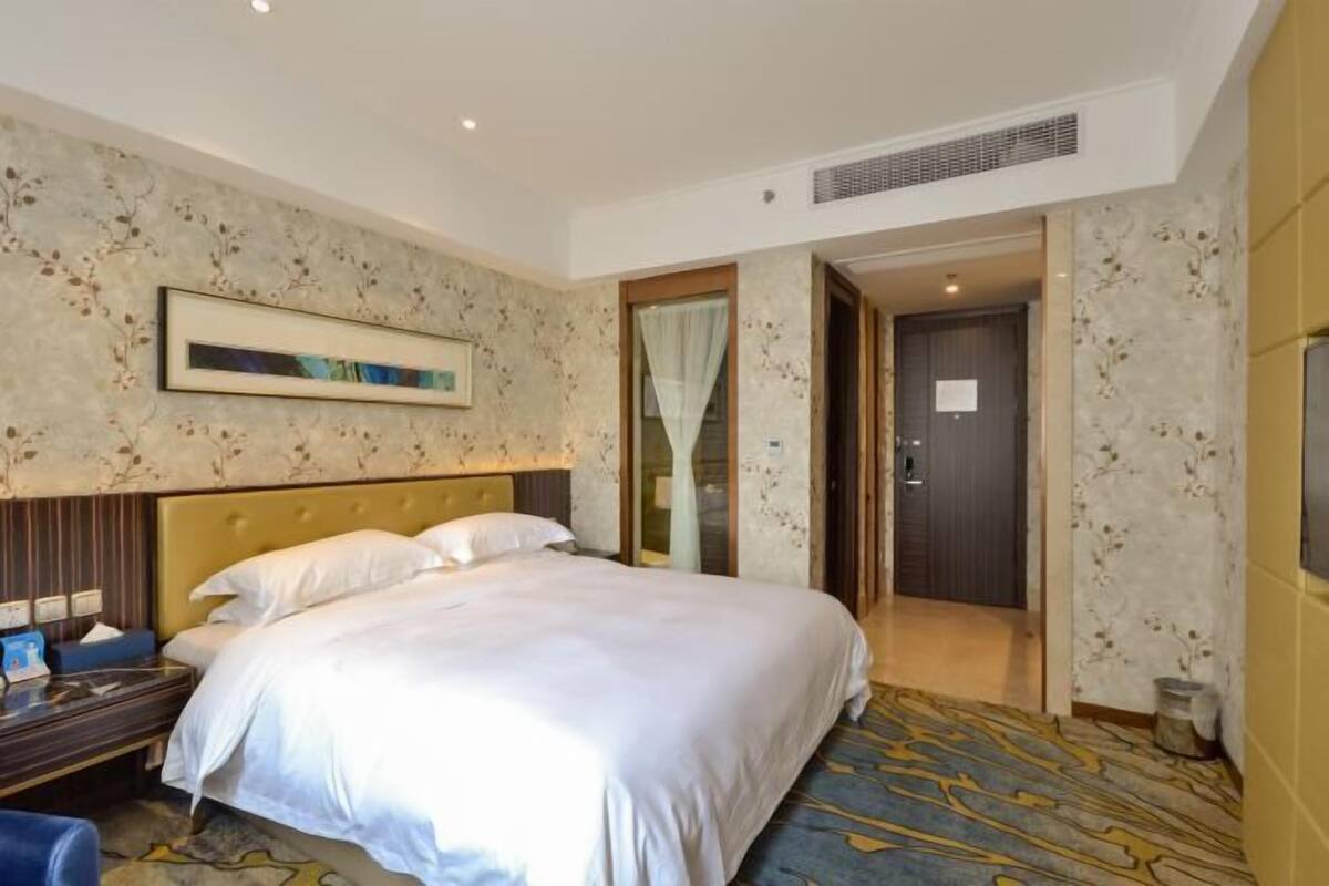 A hotel room with a large bed, a bedside table, a chair, and a TV.