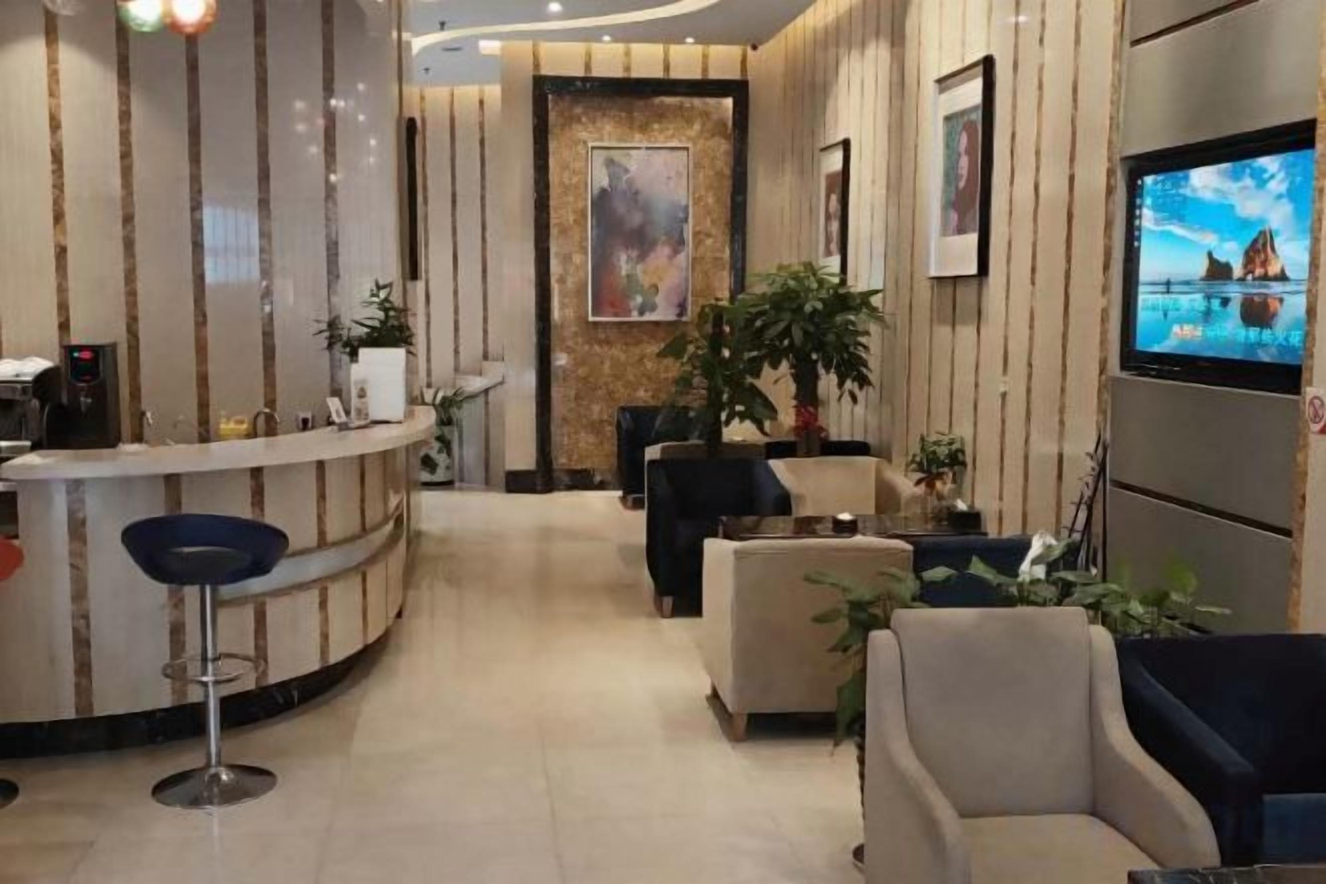 Een hotel lobby met een receptiebalie, een zithoek en een aan de muur bevestigde televisie.