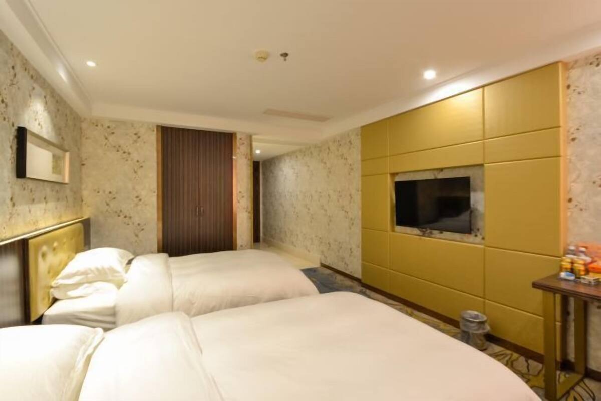 A hotel room with two beds, a television, and a small table with toiletries.