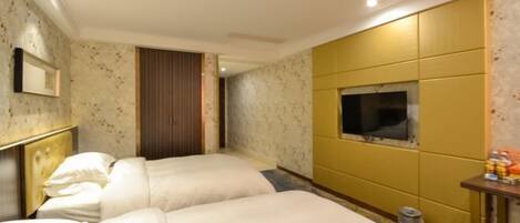 A hotel room with two beds, a television, and a small table with toiletries.