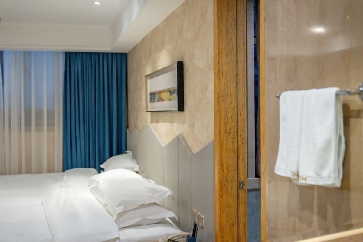 A hotel room with a bed, a wooden panel wall, a framed picture, and a towel rack.