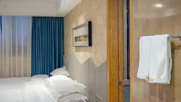 Habitación de hotel con cama, pared de paneles de madera, un cuadro enmarcado y un perchero.