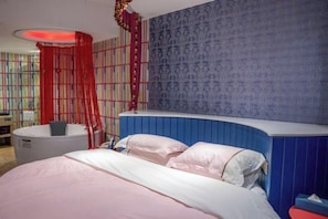 A bedroom with a bed, a nightstand, a red curtain, and a blue patterned wall.