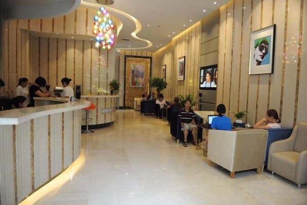 Un vestíbulo de hotel con mostrador de recepción, zona de estar y una pantalla de televisión.