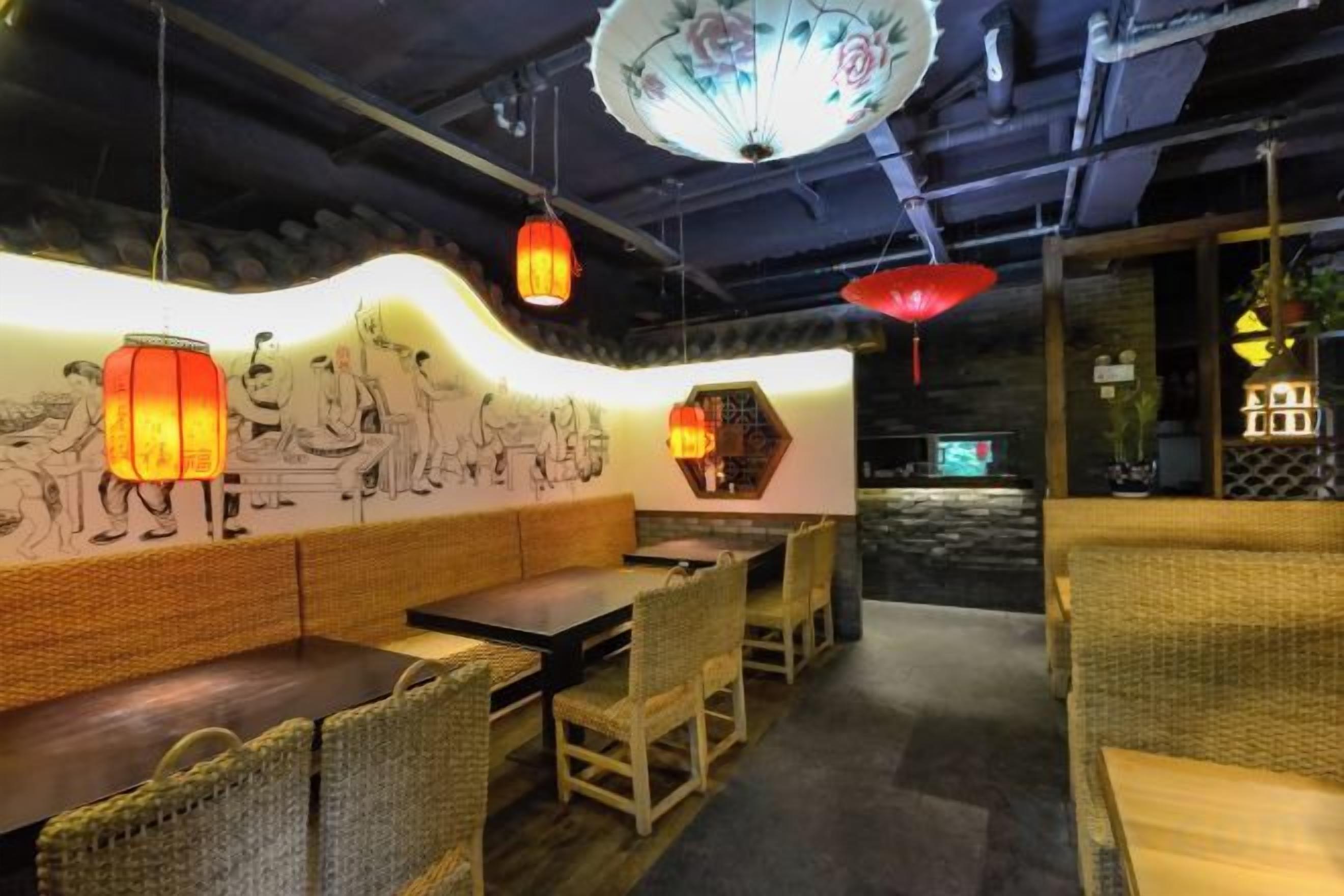Een restaurant interieur met traditionele decoratie, waaronder een muurschildering, rieten meubels en hangende lantaarns.