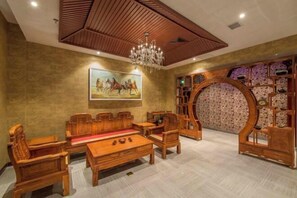 Una habitación de madera tradicional con una araña, un cuadro de caballos y una estructura circular de madera con estanterías.