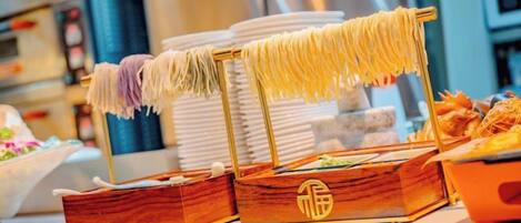 Una mesa de buffet con pasta y pan a la vista.
