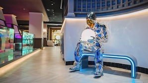 A modern interior with a unique sculpture of a figure in a reflective suit sitting on a bench. - Yinhehui Hotel (Changchun Railway Station Sasseur Zhongdong Outlet) (Changchun)