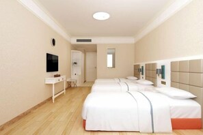 Una habitación de hotel con dos camas, un televisor, un escritorio pequeño y un espejo.