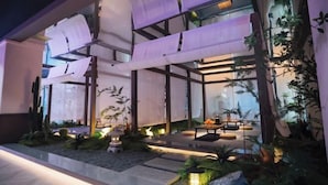 A modern building with a glass facade, outdoor seating area, and lush greenery. - Yinhehui Hotel (Changchun Railway Station Sasseur Zhongdong Outlet) (Changchun)