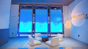 A modern hotel room with a large window, a small table, and a sofa. - Yinhehui Hotel (Changchun Railway Station Sasseur Zhongdong Outlet) (Changchun)