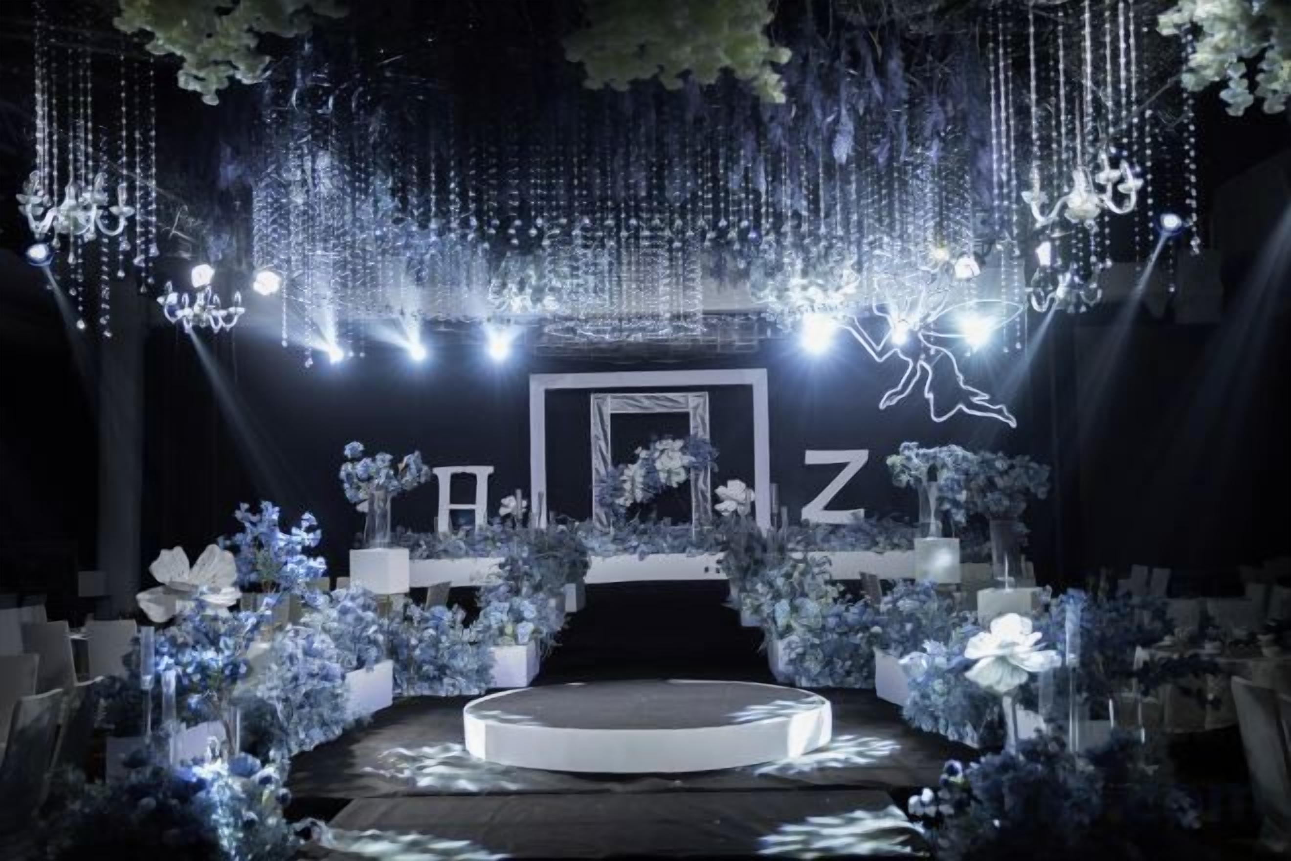 A stage with a circular platform, surrounded by floral arrangements and hanging lights.