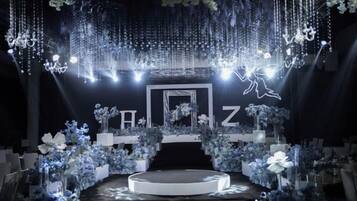 A stage with a circular platform, surrounded by floral arrangements and hanging lights.