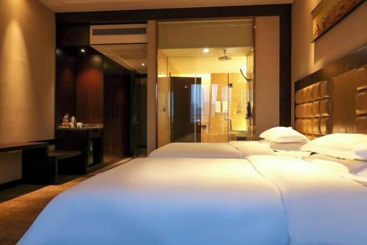 Una habitación de hotel con una cama grande, un escritorio y un espejo.