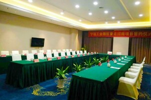 Un salón de conferencias con una larga mesa, sillas, placas de identificación y una pantalla de televisión.