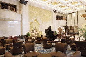 A lobby with multiple seating areas, a large decorative wall, and a staircase.