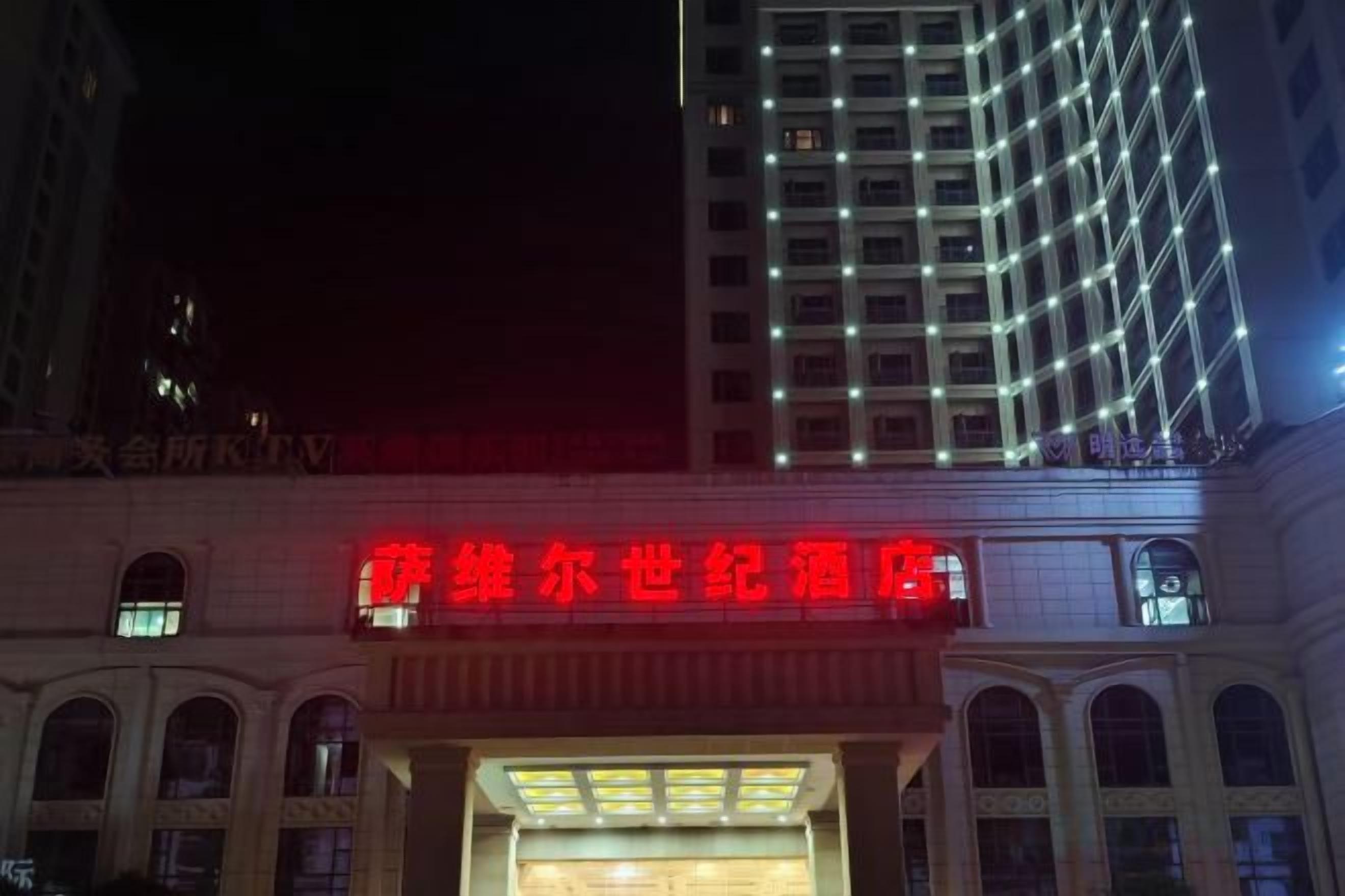 A building with a prominent red sign, arched windows, and a grid of lights on the facade.