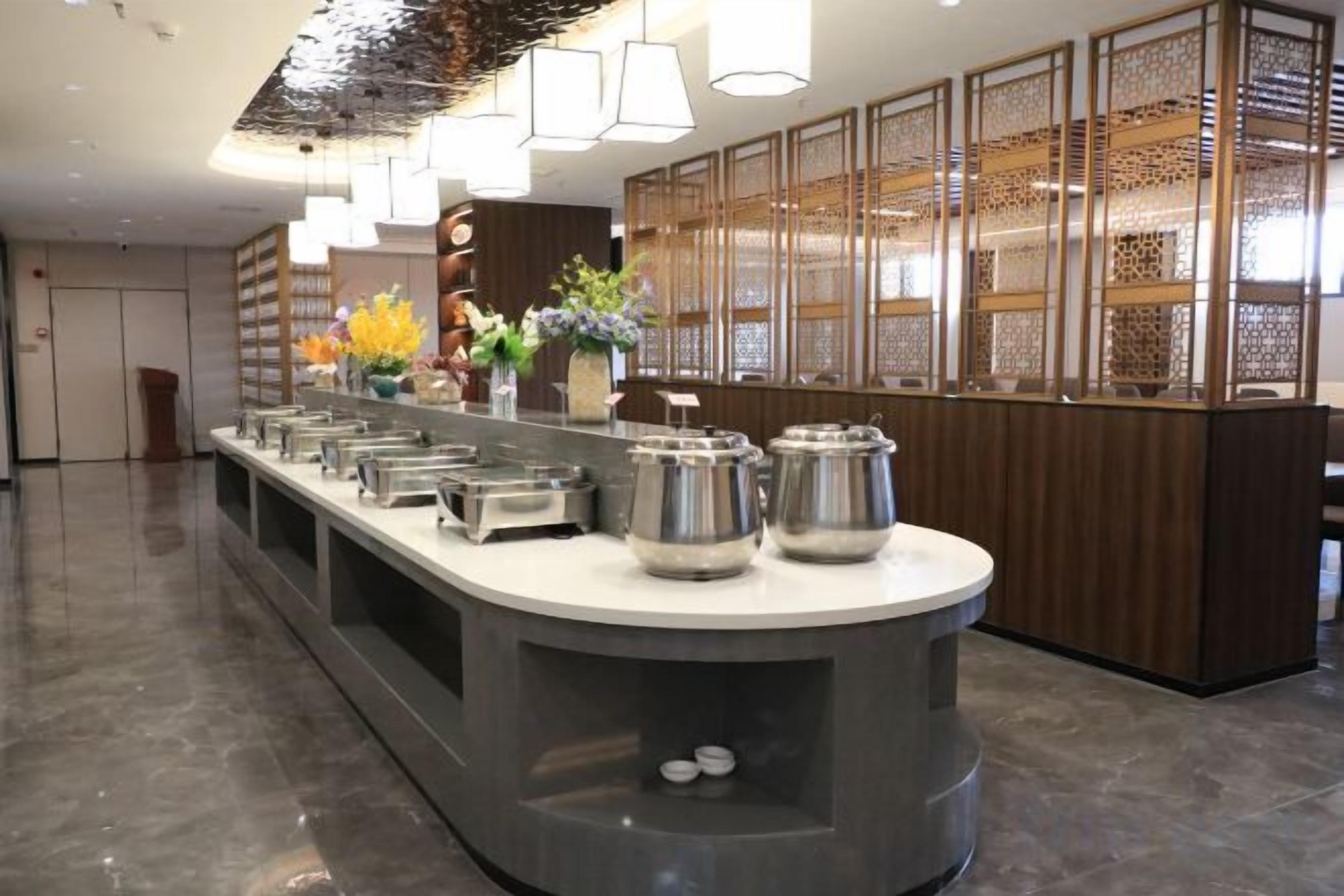 A buffet setup with multiple serving stations, a central island, and a decorative wall with a patterned screen.