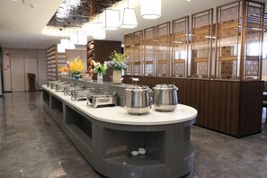 A buffet setup with multiple serving stations, a central island, and a decorative wall with a patterned screen.