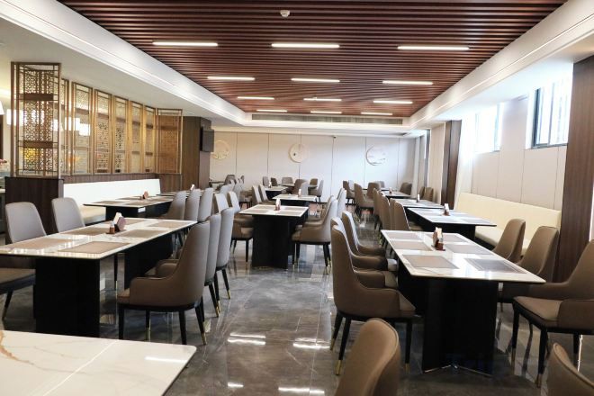 A conference room with long tables and chairs, a wooden ceiling, and a clock on the wall.