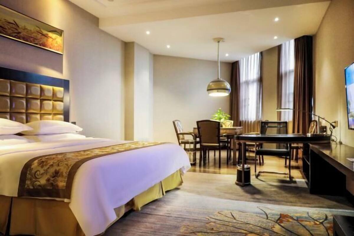 Una habitación de hotel con cama, escritorio, silla, mesa de comedor y televisor.