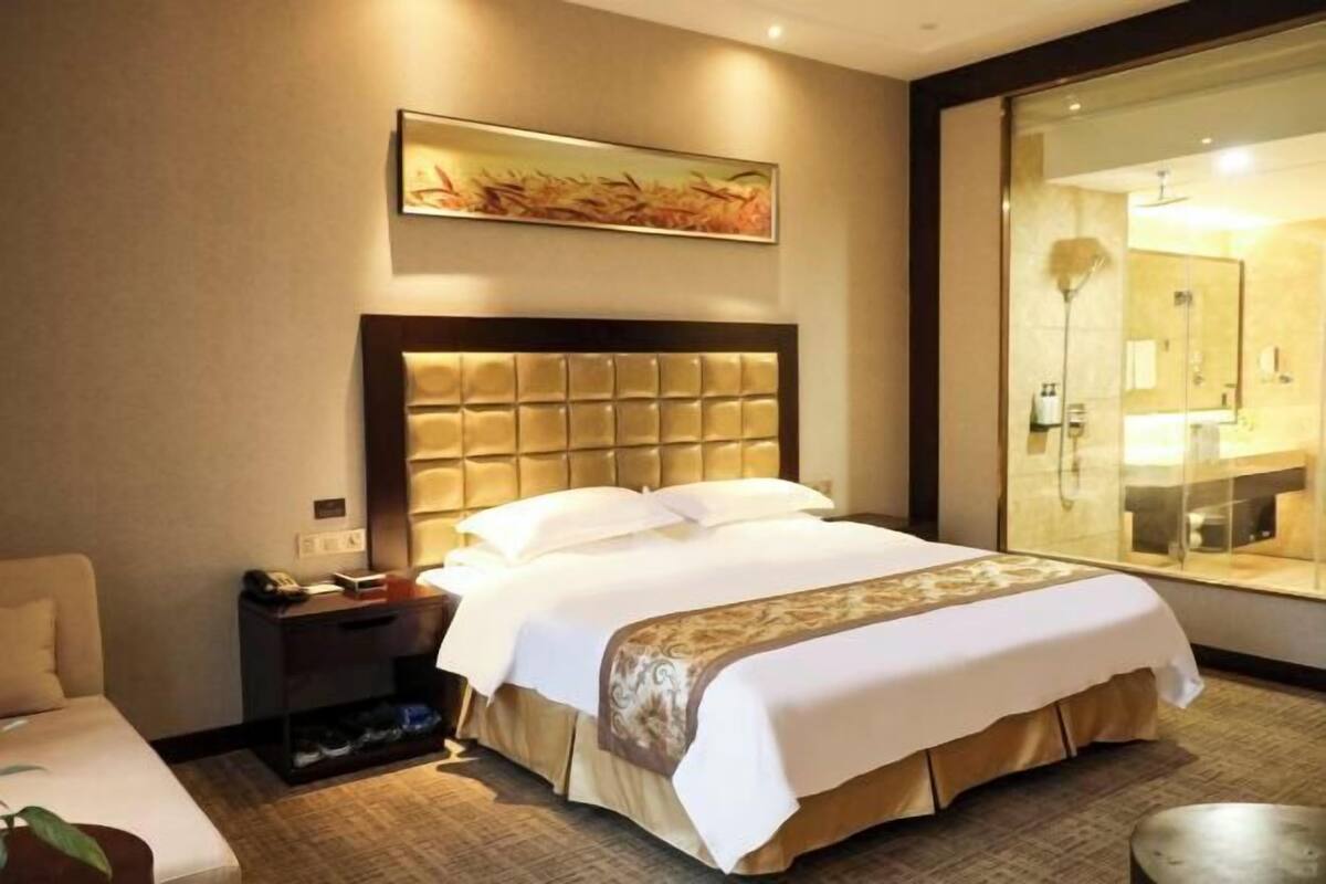 Una habitación de hotel con una cama grande, una mesita de noche y un espejo, además de una ventana.