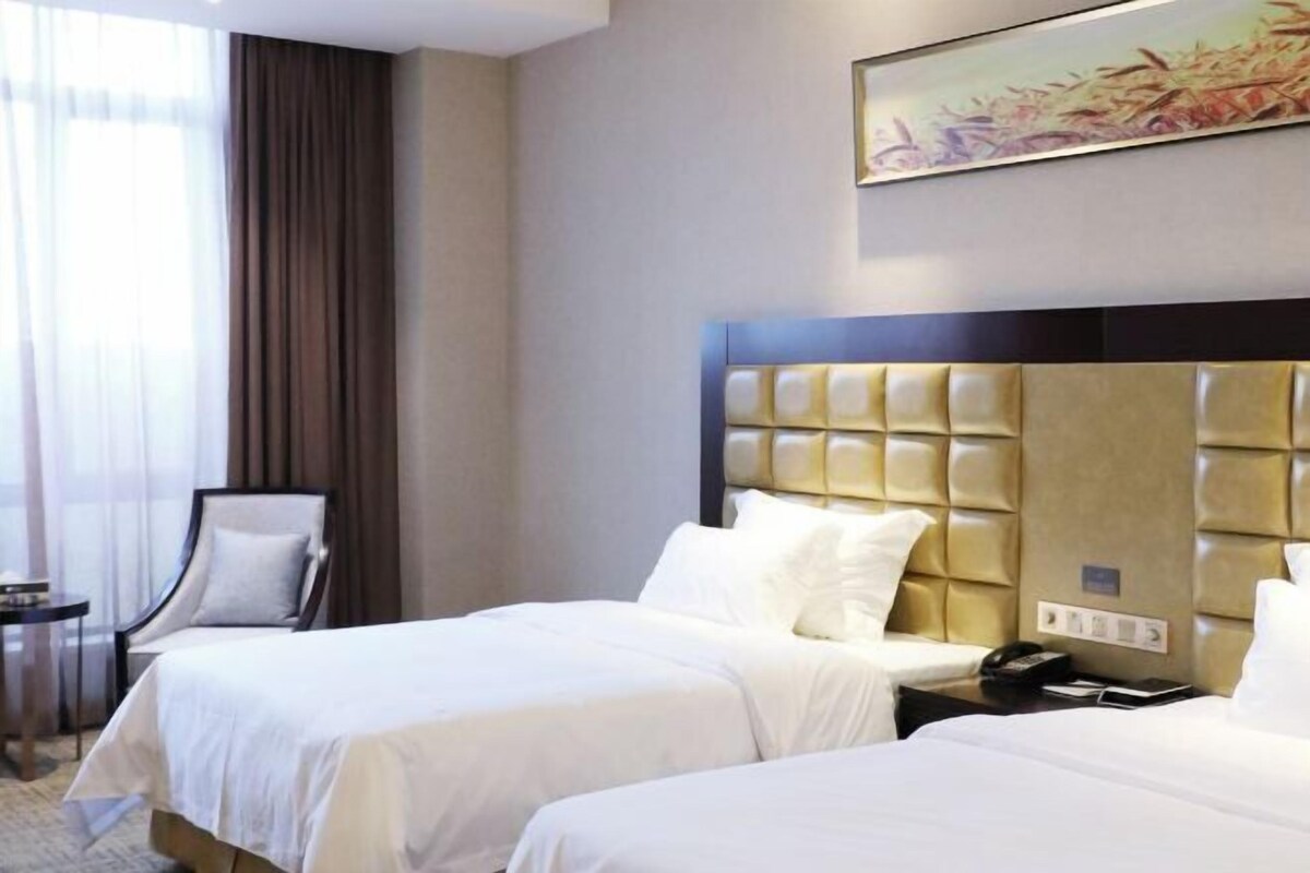 Habitació d'hotel amb dos llits, un capçal, una taula de nit amb un telèfon i una cadira.