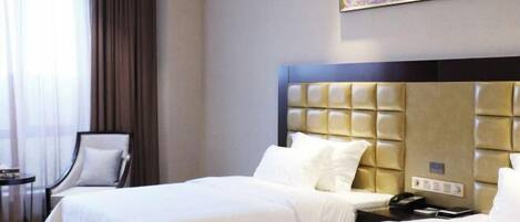 A hotel room with two beds, a headboard, a bedside table with a phone, and a chair.