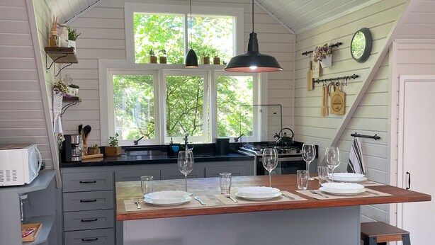 A kitchen with a central island, bar stools, and a window overlooking greenery. - Cozy apartment for your family. (RS)