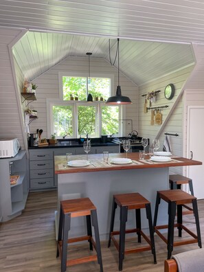 Een keuken met een centraal eiland, barstoelen en een raam met uitzicht op groen.