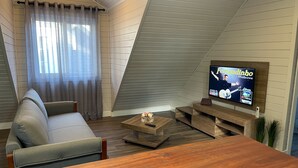 A modern living room with a sofa, coffee table, and TV mounted on a sloped ceiling. - Cozy apartment for your family. (RS)