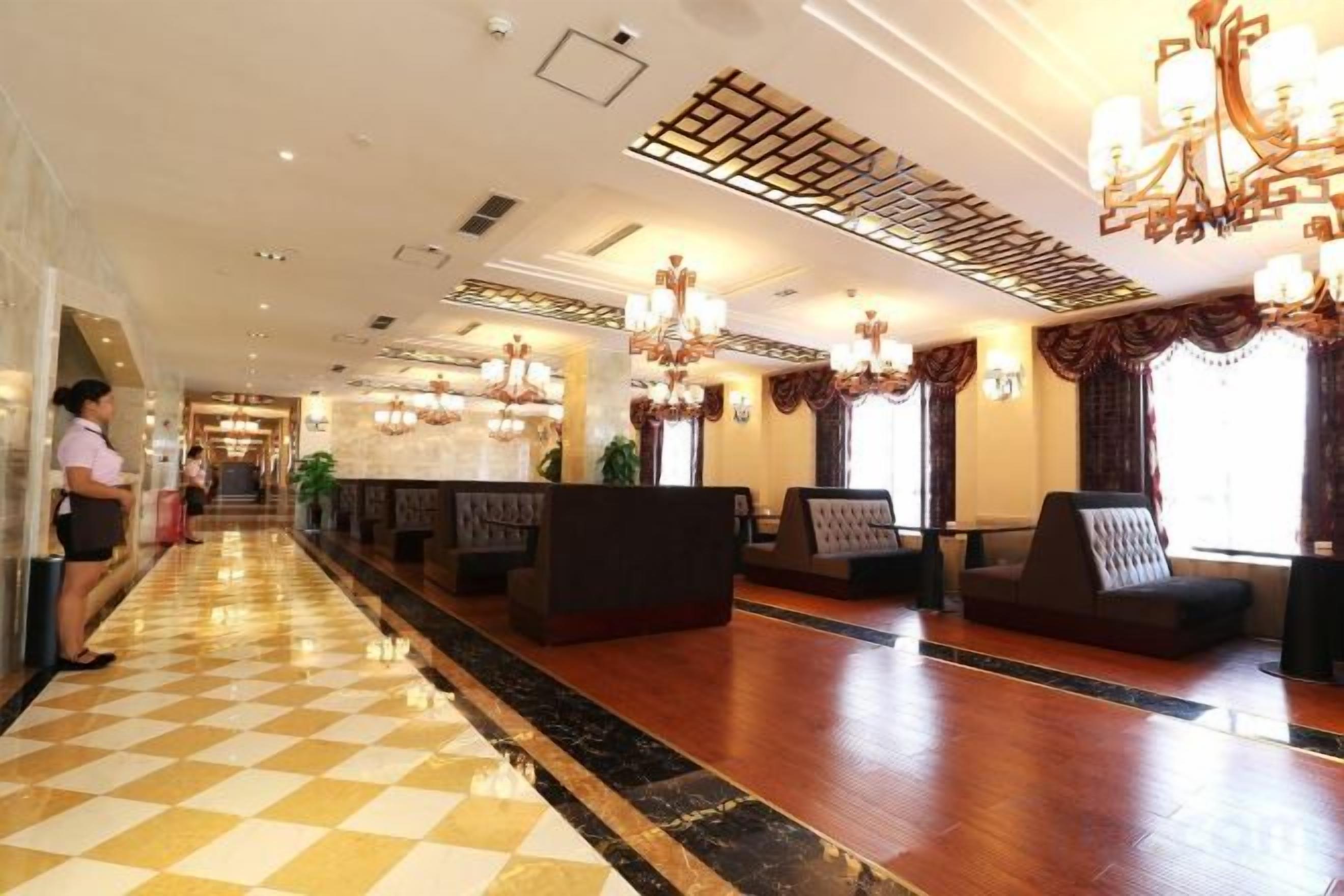 Vestíbulo de hotel con piso a cuadros, zonas de estar y candelabros.