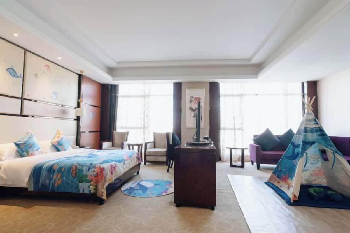 A hotel room with a bed, a desk, a chair, a sofa, and a teepee.