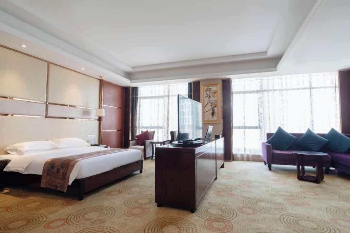 A hotel room with a bed, desk, and a sofa.