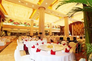 A banquet hall with round tables, white chairs, and floral decorations. - Guoneng Grand Hotel (Dianjiang County)