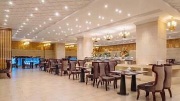 A spacious hotel lobby with multiple seating areas, a reception desk, and decorative lighting.