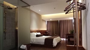A modern hotel room with a large bed, a shower area, and a wooden chair.