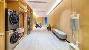A laundry room with built-in washers and dryers, a bench, and exercise equipment.