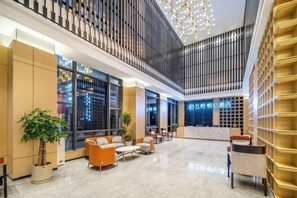 A hotel lobby with seating areas, a reception desk, and large windows offering city views. - Wuyue Yuexin Hotel (Meidi Impression Wuyue Plaza Branch) (Shangrao)