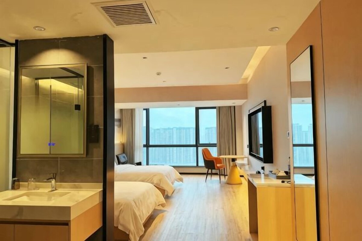 Une chambre d’hôtel avec un grand lit, un bureau, une chaise, une télévision et une salle de bain équipée d’un miroir et d’un lavabo.