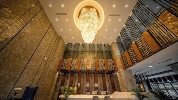 A modern hotel lobby with a central reception desk, seating area, and a large chandelier. - Bai Rui Sheng Hotel (Huaping)