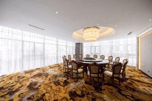 A conference room with a round table, chairs, and a chandelier. - Bai Rui Sheng Hotel (Huaping)