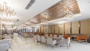 A spacious, modern dining area with high ceilings, contemporary lighting fixtures, and a mix of seating arrangements including tables and booths. - Bai Rui Sheng Hotel (Huaping)
