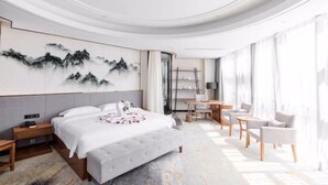 A modern hotel room with a large bed, a desk, and a seating area. - Bai Rui Sheng Hotel (Huaping)
