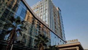 A modern high-rise hotel with reflective glass facade, palm trees in the foreground, and a clear sky. - Bai Rui Sheng Hotel (Huaping)