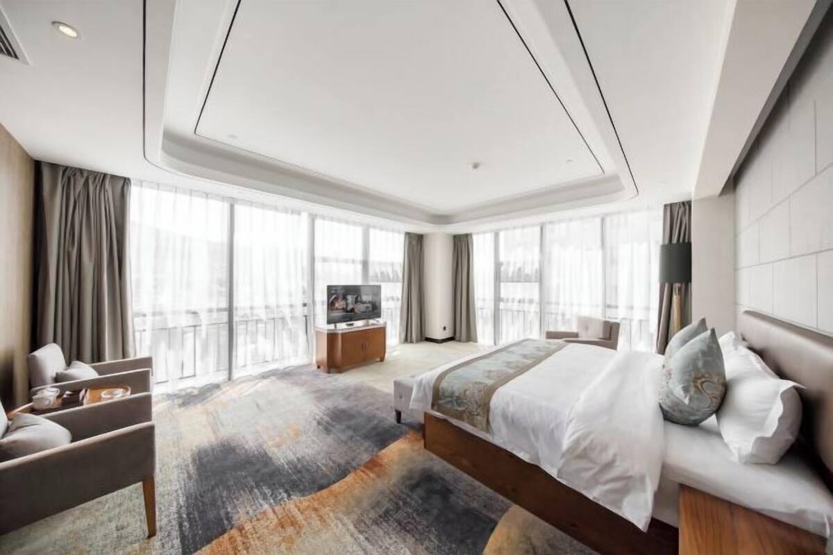 A modern hotel room with a large bed, a TV, and a balcony view.