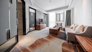 A modern living room with a sofa, coffee table, and a TV. - Bai Rui Sheng Hotel (Huaping)